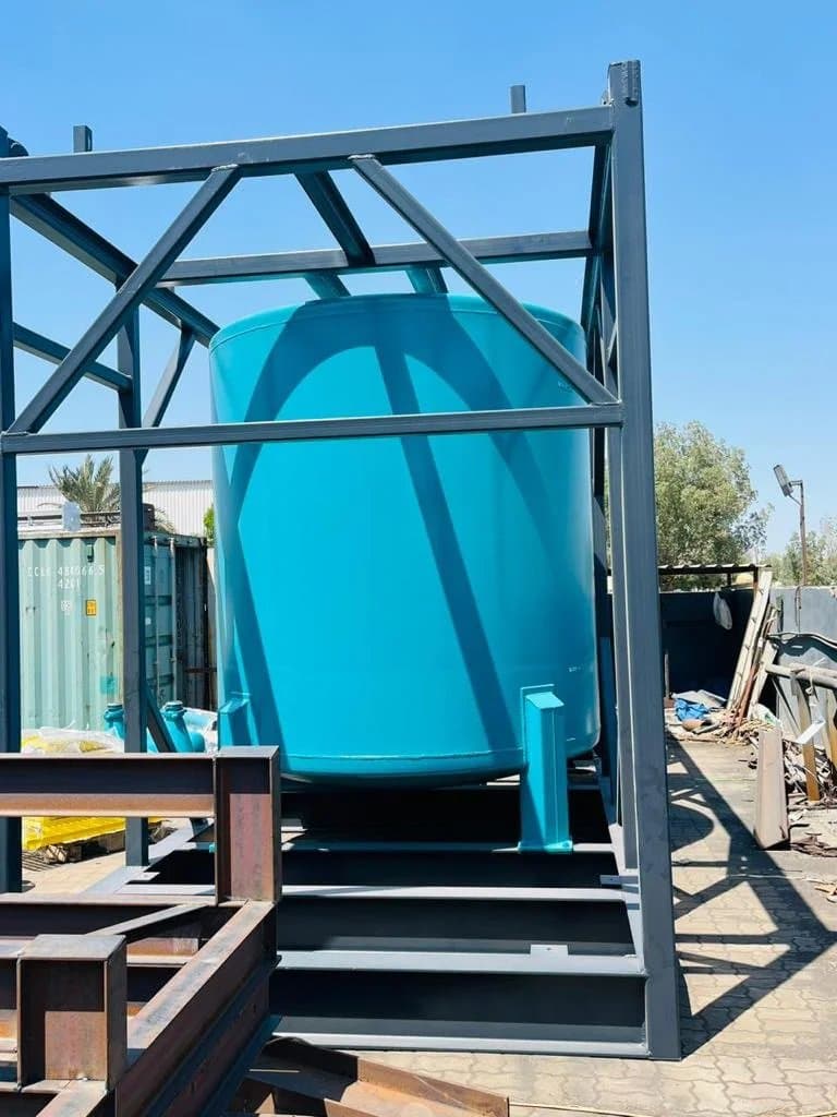 Blue tank installed in a fabricated steel support frame in the workshop yard